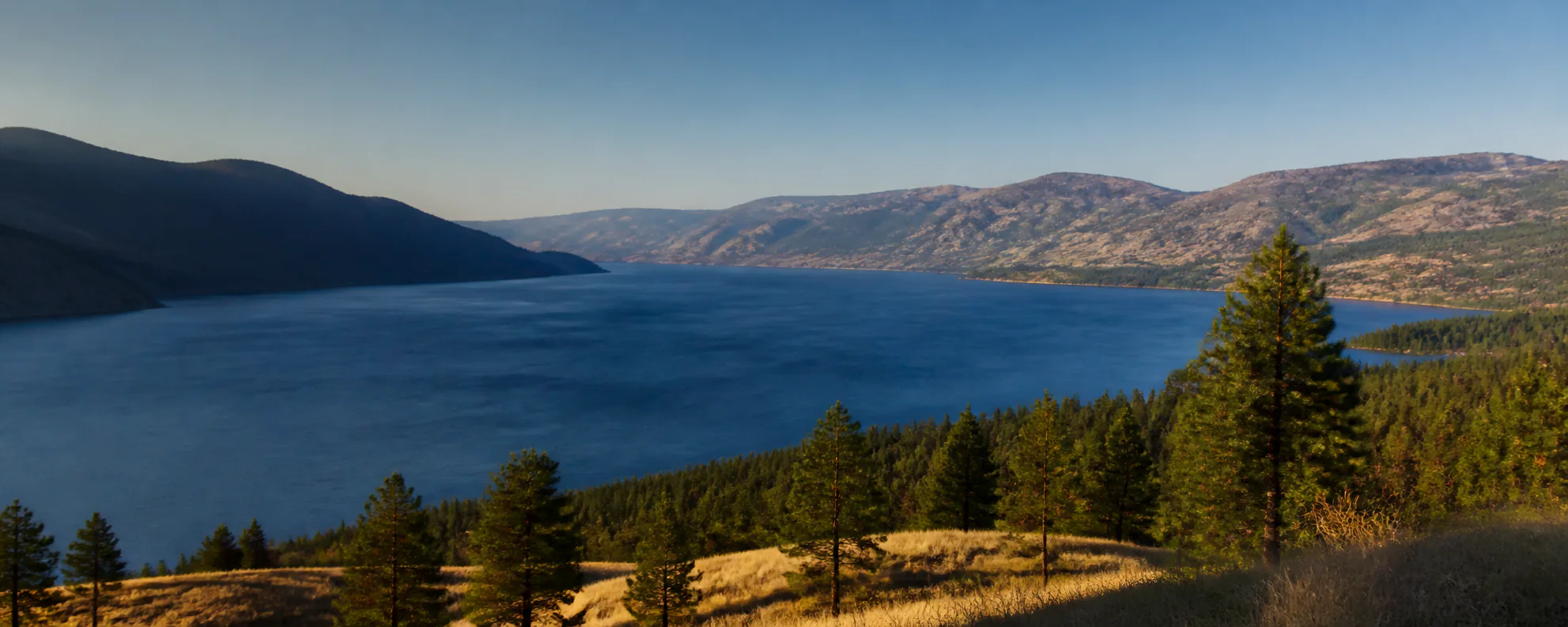 Okanagan Lake framed by pine-covered hills and mountain ridges in British Columbia